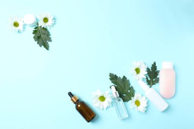 Renkli arkaplanda kozmetik krem ve çiçek şişeleri