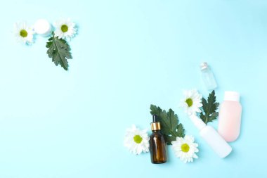 Mavi arka planda kozmetik ürünleri ve çiçek. düz yatar, üst görünür, düz uzanır.