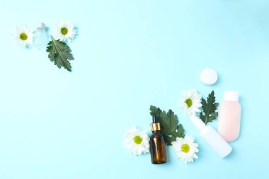 Mavi arka planda kozmetik ürünler, çiçekler, krem ve haplar. Bir ceset için doğal kozmetik ürünler. Doğal güzellik. Doğal kozmetik ürünleri. düz yat.