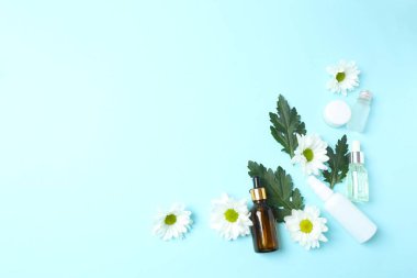 Kozmetik krem şişesi, papatya çiçeği ve açık mavi arka planda papatya çayı.