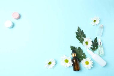 Renk zemininde papatya çiçekleri olan bir şişe gerekli yağ.