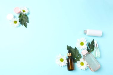 Renk arkaplan üzerinde kozmetik ürünleri ve çiçeklerle düz konum
