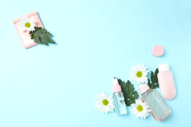 Kozmetik şişe, çiçek ve yapraklar renk arka planında