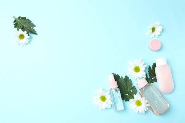 Kozmetik krem düzlüğü, mavi arka planda bir şişe su ve çiçek. güzellik konsepti.