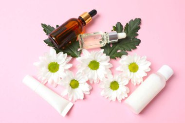 Pembe arka planda gerekli yağ şişeleri ve çiçekler