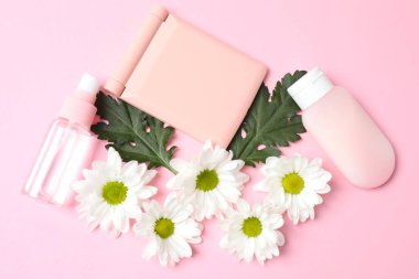 Pembe arka planda çiçekli kozmetik ürünleri