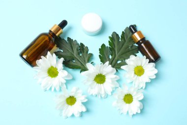 Bir şişe papatya yağı, haplar ve çiçeklerle.