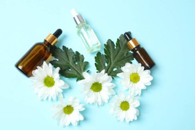 Beyaz arka planda bir şişe ve bir bardak papatya yağı.