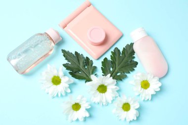 Kozmetik şişesi, çiçekler ve pastel renkli arka planda nane yaprakları. Düz yatış, üst manzara. Doğal organik kozmetik konsepti