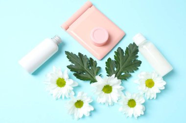 Renk arkaplanında kozmetik için çiçek ve şişe içeren düz konum