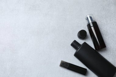 Siyah parfüm şişesi ve gri arka planda boş kağıt.