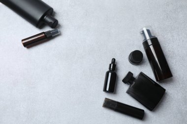 Gri mermer arka planda siyah kozmetik ürünleri olan düz bir kompozisyon. Metin için boşluk