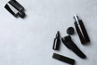 Siyah kozmetik seti, makyaj fırçası ve gri arka planda göz farı olan bir şişe. Üst görünüm, düz uzanma