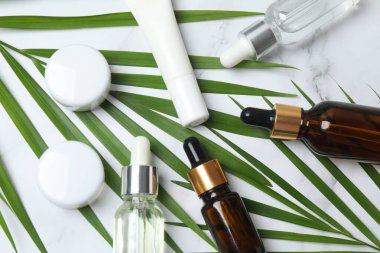 hafif arka planda kozmetik şişeleri, yağ ve palmiye yaprakları ile bileşim