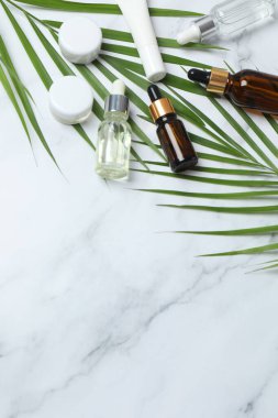 Hafif mermer zemin üzerinde şişe ve palmiye yaprağı olan kozmetik serumu