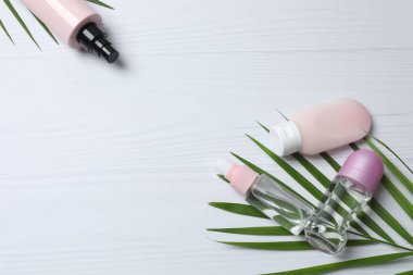 Kozmetik krem şişesiyle kompozisyon, beyaz arkaplanda çiçekler