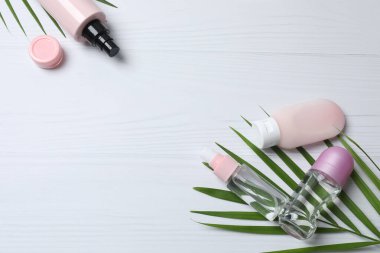 Beyaz arka planda kozmetik şişeleri ve çiçekleri olan kompozisyon