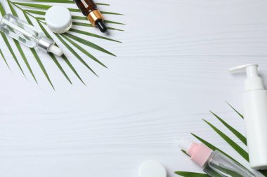 Beyaz arka planda palmiye yaprakları olan kozmetik ürünleri. düz yat