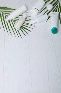Hindistan cevizli kozmetik şişeleri ve beyaz arka planda palmiye yaprakları düz.