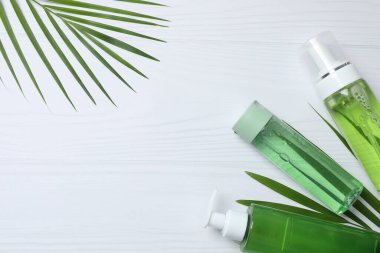 Işık arka planında gerekli yağ şişesi ve tropikal yapraklarla bileşim