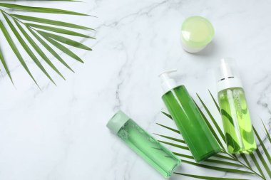 Kozmetik şişesi, yeşil yapraklar, kozmetik yağ şişeleri ve beyaz mermer zemin üzerinde taze yeşil okaliptüs düzleştirilmiş. Boşluğu kopyala, üst görünüm