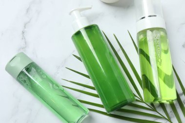 açık gri masa üzerinde aloe yaprakları ve bir şişe serum ile kompozisyon