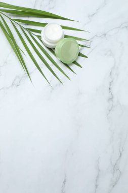 Yeşil yapraklı doğal kozmetik krem mermer arka planda, düz yerde. Metin için boşluk