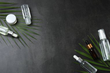 Kozmetik şişeleri ve açık gri arkaplanda yaprakları olan kompozisyon