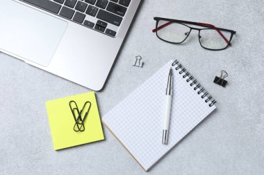 Gri arka planda ofis aksesuarları olan düz bir kompozisyon. Metin için boşluk