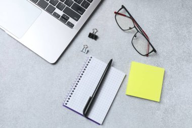 Bilgisayarlı, kırtasiyeli, not defterli ve gri arka planlı gözlüklü bir ofis. en üstteki görünüm