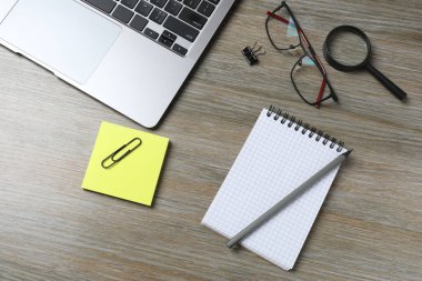 Ofis malzemeleri, defter, bilgisayar ve kalem ahşap masa arkasında.