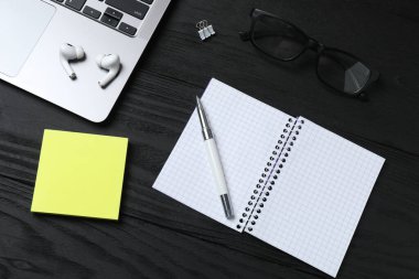 Modern ofis malzemeleri ve siyah mermer masaya dizilmiş dizüstü bilgisayarı olan düz bir yapı.