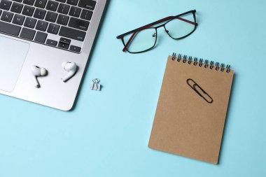 Renk arkaplanına dizüstü bilgisayar, kırtasiye ve gözlük konumu