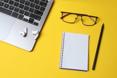 dizüstü bilgisayarı, gözlükleri ve renk arkaplanındaki not defteriyle düz konum