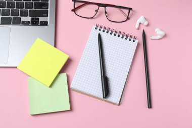 Düz konum dizüstü bilgisayar, not defteri ve pembe arka planda kalem. Metin için boşluk