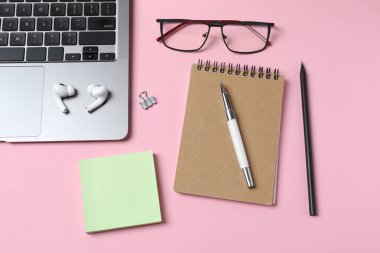 Düz konum dizüstü bilgisayar, gözlük ve pembe arka planda not defteri. Metin için boşluk