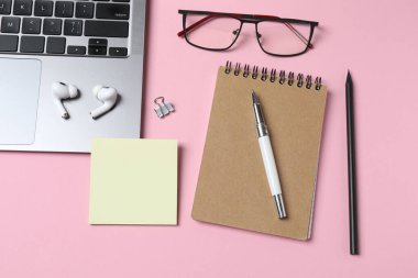 Dizüstü bilgisayarı, defteri, kalemi, kalemleri, kalemleri, kalemleri ve pembe arka planı olan düz bir ofis masası. çalışma alanı veya masa konsepti.