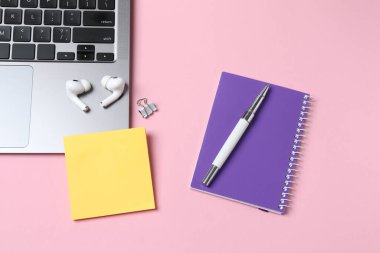 Dizüstü bilgisayar, defter, kulaklık, not defteri, pembe arka planda kalem ve kahve fincanı. düz yat