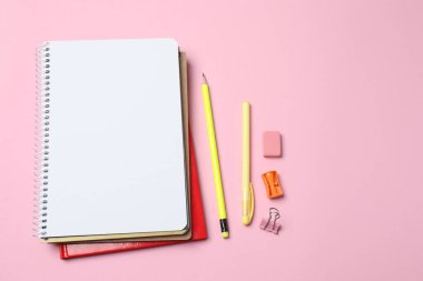 defter ve kalemler, pembe arkaplan, düz yatış