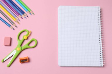 Okul konseptine dönelim. Pembe arka planda renkli defterlerin, kalemlerin ve diğer malzemelerin üst görünümü