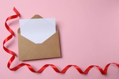 Boş kağıt kart ve pembe arkaplanda kırmızı fiyonk olan zarf