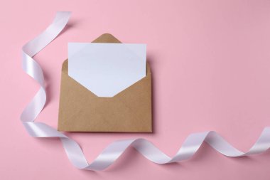 Üzerinde kurdele ve pembe arkaplan olan bir zarf..