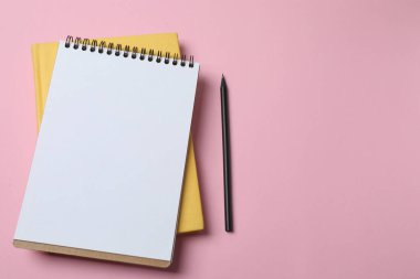 Pembe arka planda boş bir not defteri ve kalem..