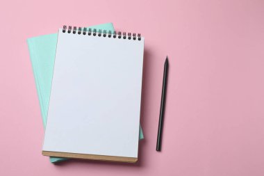 Pembe arka planda boş beyaz defter ve kalem. düz yat