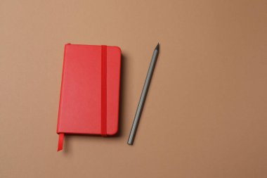 Kırmızı zemin üzerinde defter olan kırmızı kalem