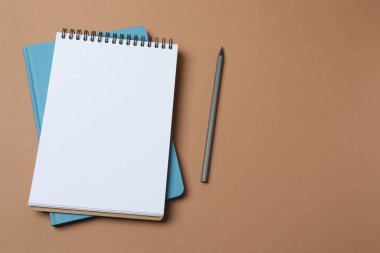 Mavi arkaplandaki boş defter ve kalemle fotokopi alanının üst görüntüsü, tasarım için hazırlan. Düz yat. asgari yaratıcı çalışma alanı