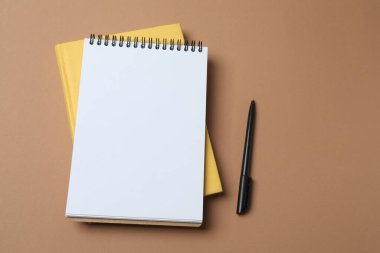 Sarı arkaplandaki sarı boş not kağıdıyla kalem..