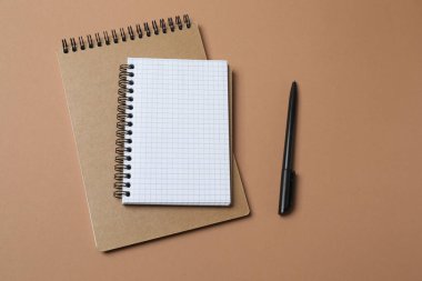 Kahverengi arkaplandaki defteri kalem ile aç.