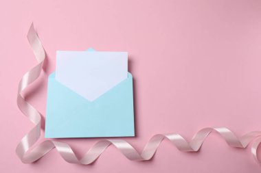 Zarf ve boş kart pembe zemin üzerinde kurdele ve pembe zarf ile mesajınız için boş alan.