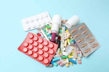 İlaç, eczane ve sağlık konsepti - mavi arka plandaki ilaç ve kapsüllerin üst görünümü